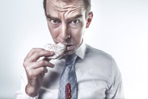 Man eating jelly filled donut with jelly on his tie