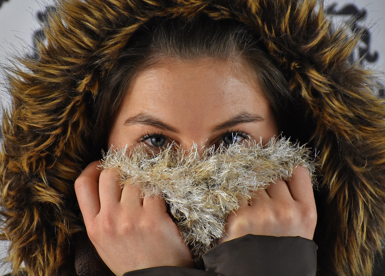 Girl wearing faux fur hood and covering her nose and mouth with a faux fur cloth