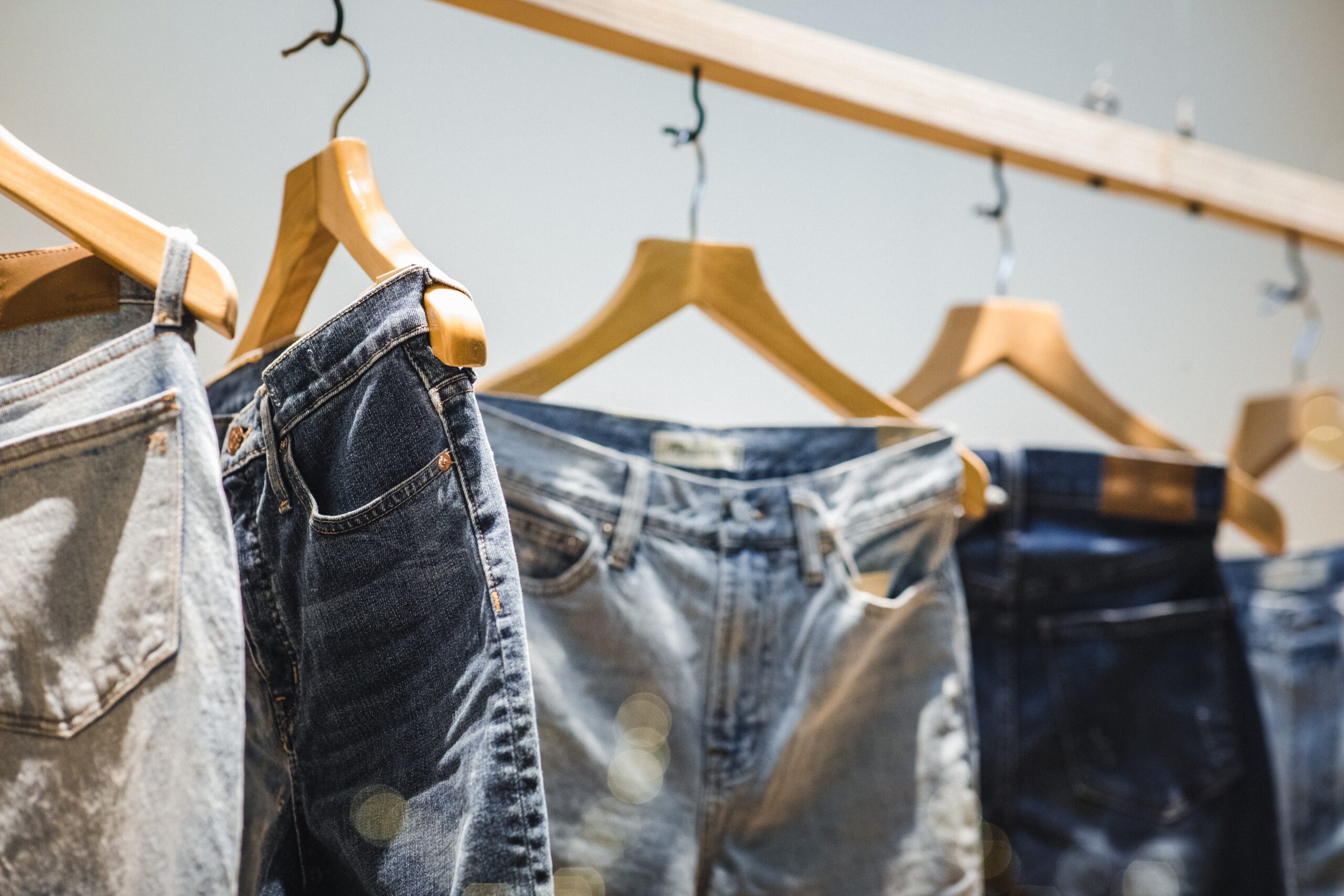 Several pairs of blue jeans hanging on rack