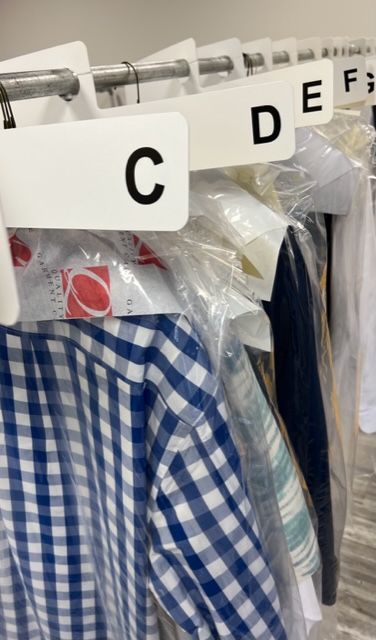 clothes hanging on a dry cleaners rack covered with plastic bag